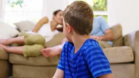niño jugando frente a la cámara con los padres detrás