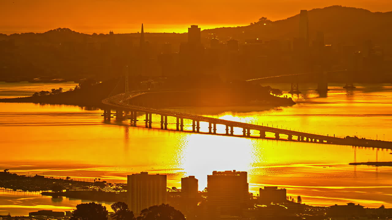 Time-lapse of Oakland Bay Bridge and San Francisco skyline reflecting golden sunset