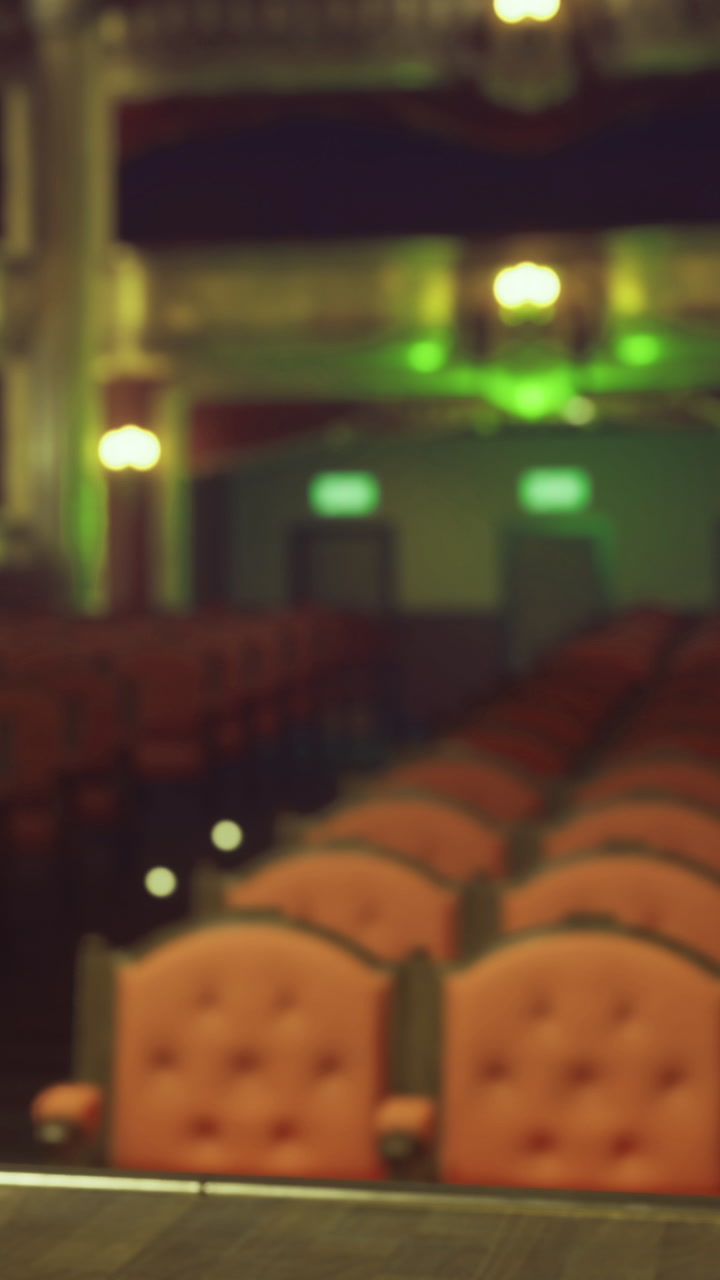 Empty theater seats are arranged in rows with green lights in the background