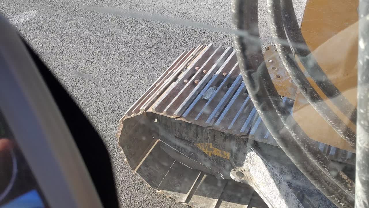 아스팔트를 가로질러 운전하는 굴삭기 트랙의 진동하는 더러운 창을 통해 1인칭 보기