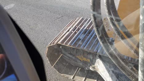 vista en primera persona a través de una ventana sucia vibrante de pistas de excavadoras que conducen a través del asfalto
