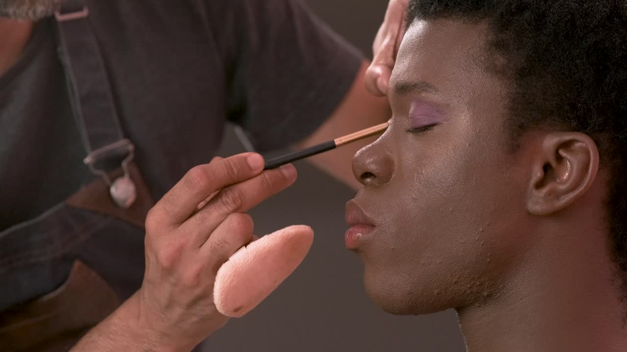 Crop visagiste filling in eyebrows of black transgender