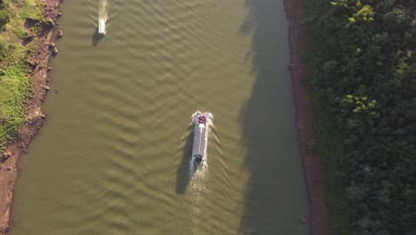 toma aérea de arriba hacia abajo de los barcos turísticos que navegan por el río iguazú durante el día soleado - frontera del río argentina y brasil en el día soleado