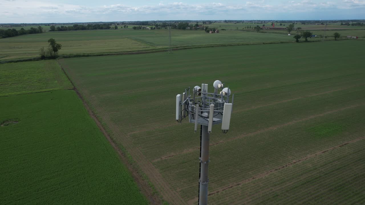 5G cellular antenna tower rises against a cloudy sky, with panel antennas and radio equipment mounted on a steel mast,