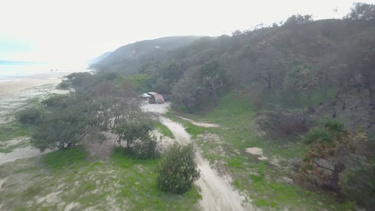 Aerial Drone shot towards a campsite, on a white sand beach, on Double island, in Queensland, Australia