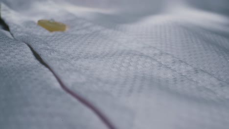 this is a detailed closeup view of a classic white shirt showcasing its button and the beautifully textured fabric
