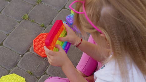 Child-girl-playing-colorful-squishy-silicone-bubbles-sensory-toy-simple-dimple-pop-it-game,-close-up