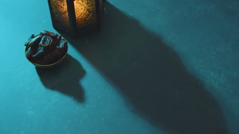 high angle tracking shot of some dates water beads and lantern on table