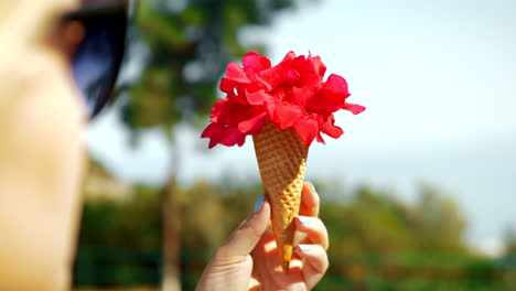 mujer sosteniendo flores rojas en cono de waffle