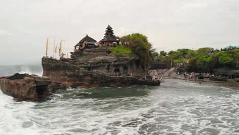 drone flying closely over the popular pura tanah lot temple in bali