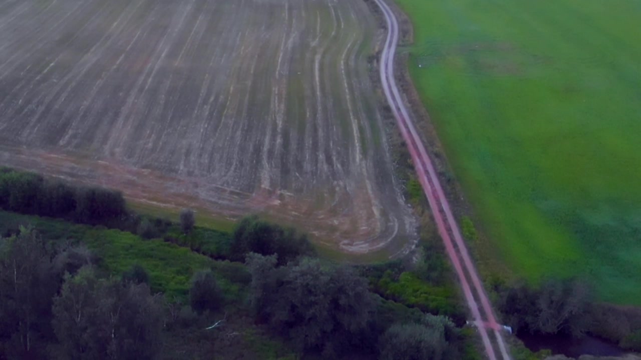 Drone che scende lentamente e si inclina verso l'alto sopra i campi