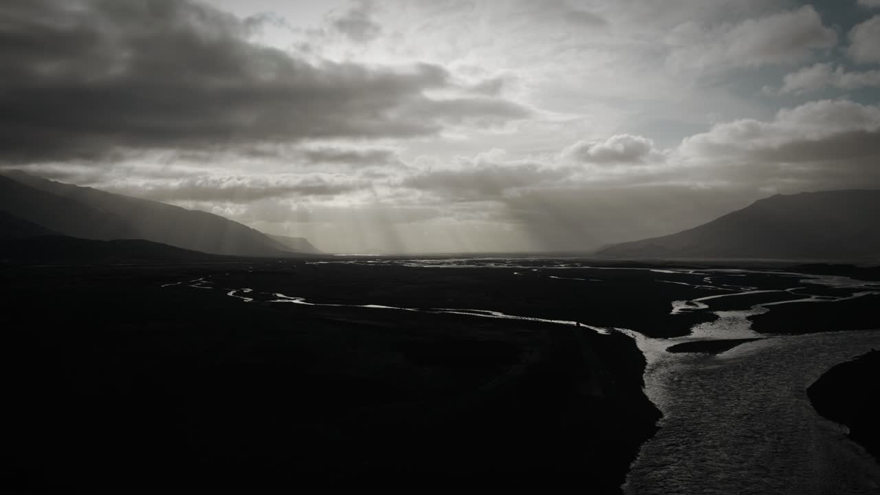 Aerial flying up in thor valley, flying over glacial river flowing through black volcanic floodplain, thorsm&ouml;rk dramatic moody landscape Iceland