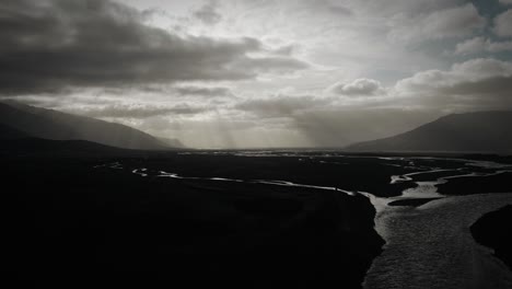 aerial flying up in thor valley, flying over glacial river flowing through black volcanic floodplain, thorsmörk dramatic moody landscape iceland