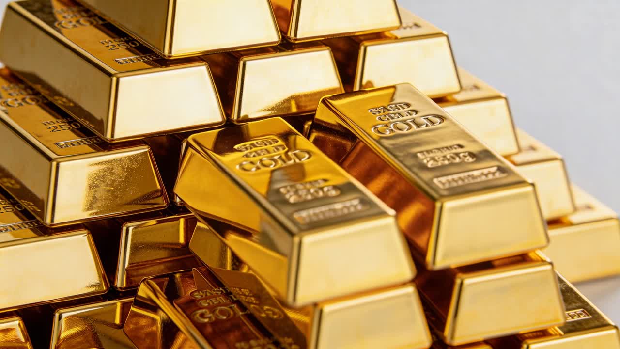 Telecamera in movimento che rivela una pila piramidale di lingotti d'oro su un tavolo chiaro, evidenziando le marcature stampate.