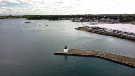 Circling-drone-footage-of-a-small-light-beacon-at-the-edge-of-a-jetty-in-Salem,-Massachusetts