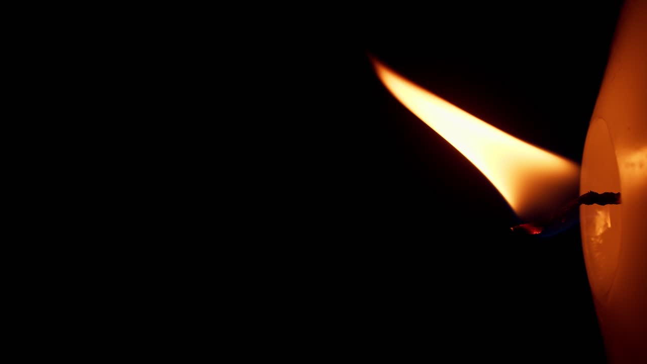 rotación vertical de las luces de llama de una sola vela amarilla grande aisladas en un fondo negro