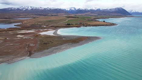 turquoise water of lake tekapo in daytime in canterbury, south island, new zealand. - aerial shot