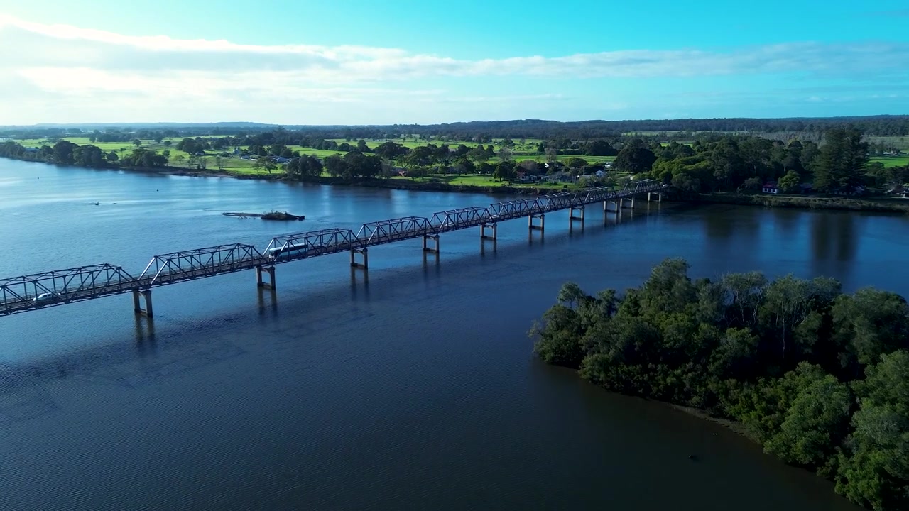 Paesaggio aereo da drone di autobus e auto che attraversano il ponte Martin sull'insenatura del fiume Manning a Taree, con la campagna rurale sullo sfondo, sulla Mid North Coast australiana