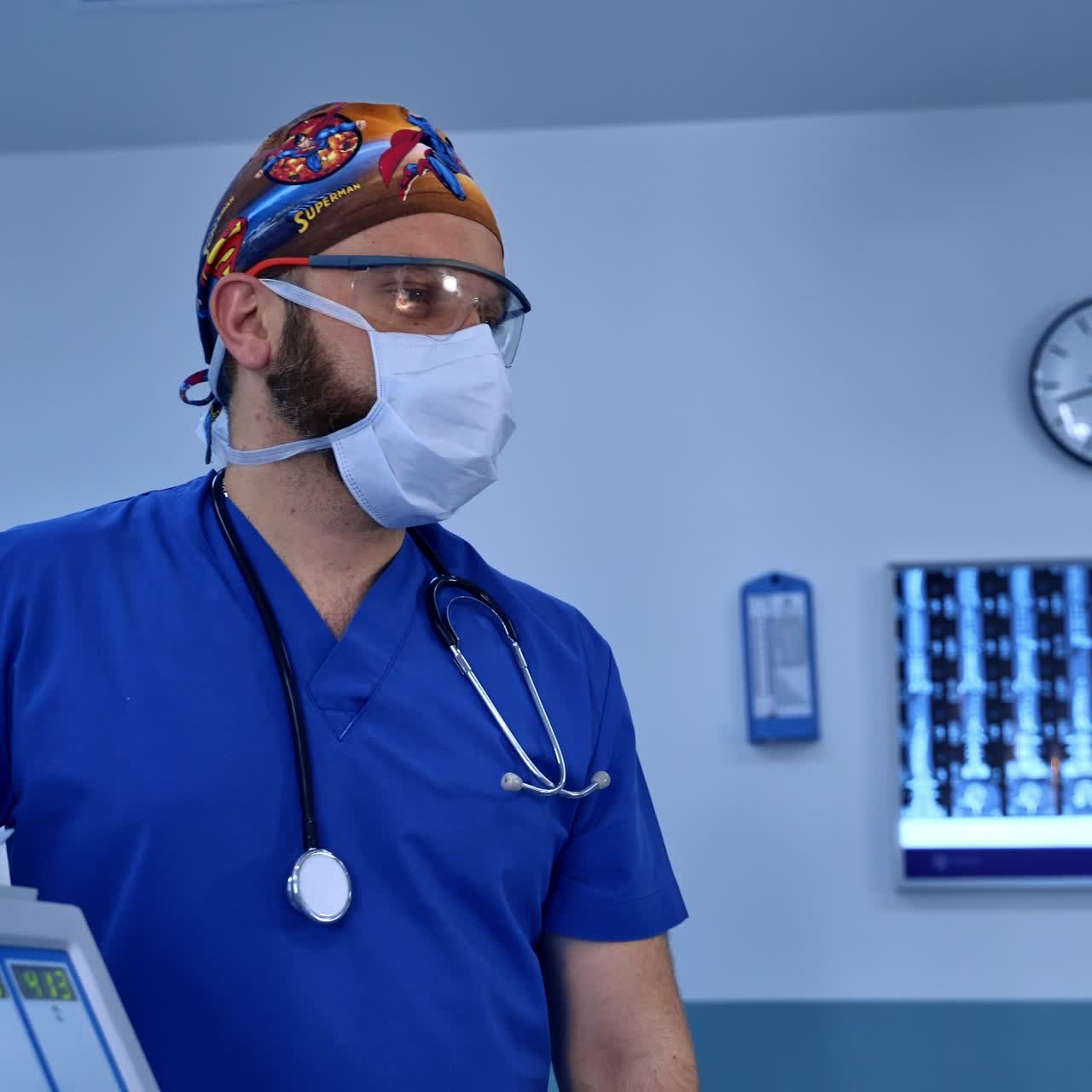 Anestesista con barba comprobando el funcionamiento del equipo en el quirófano. Médico con estetoscopio en los hombros en el hospital.