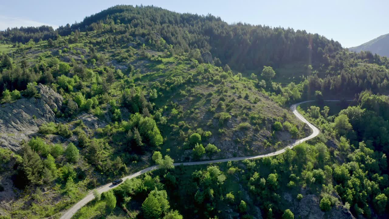 vista aérea que muestra el coche en la carretera en las montañas verdes de rodope durante un día soleado en bulgaria