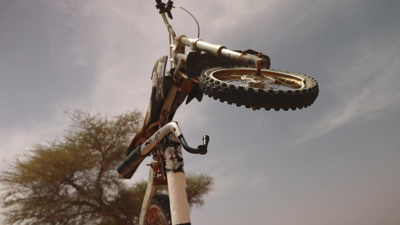 Motocross dirt bike rearing up vertically performing a stunt wheelie against a cloudy sky in the Sahara Morocco