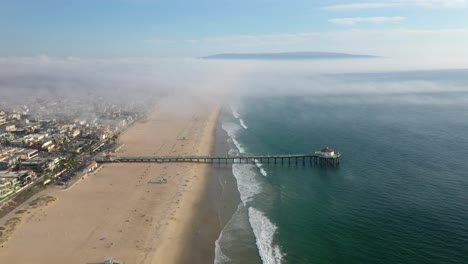 manhattan beach pier on a misty day in california, united states - aerial pullback