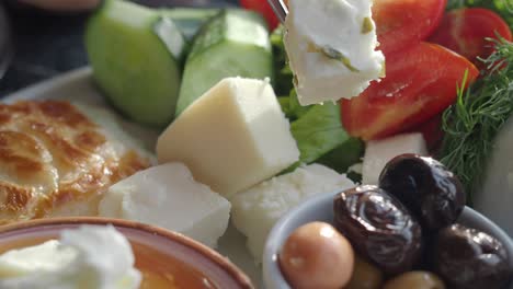 a turkish breakfast plate with cheese, olives, tomatoes, cucumber, and pastry