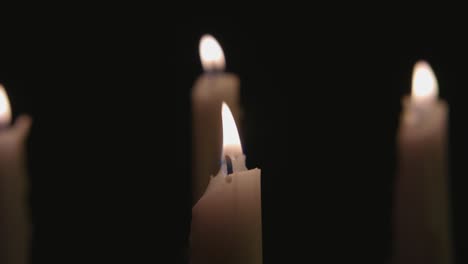 four white candles lit then three are blown out by the wind