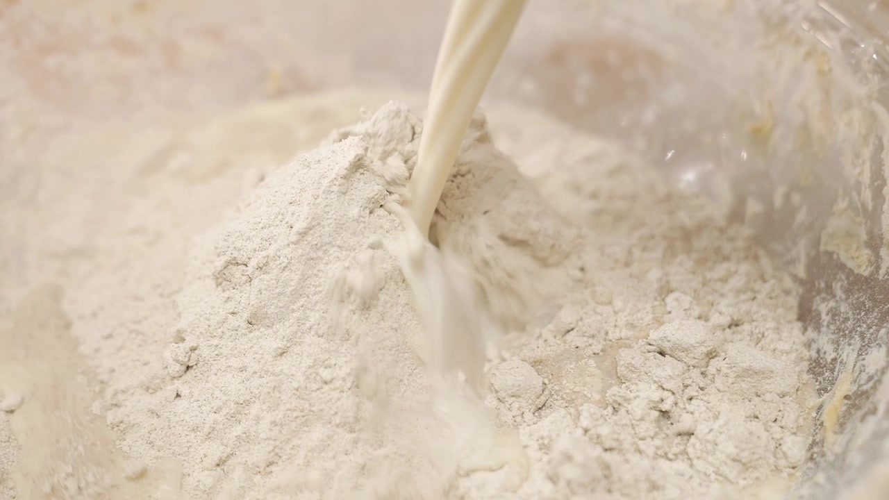 Menuangkan Susu ke dalam Tepung untuk Menyiapkan Adonan Kue