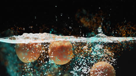 composition of green leaves over oranges floating in water on black background