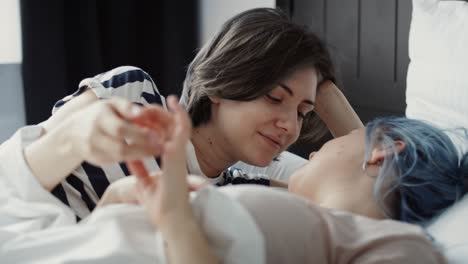 video of romantic lesbian couple holding hands in the bed