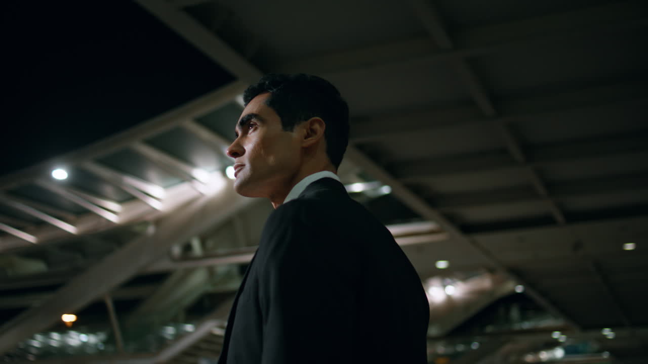 empleado tranquilo admirando la arquitectura de la noche vista trasera. hombre yendo al aeropuerto oscuro