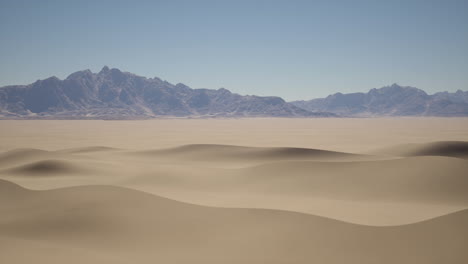 paisaje desértico con dunas de arena y montañas en la distancia