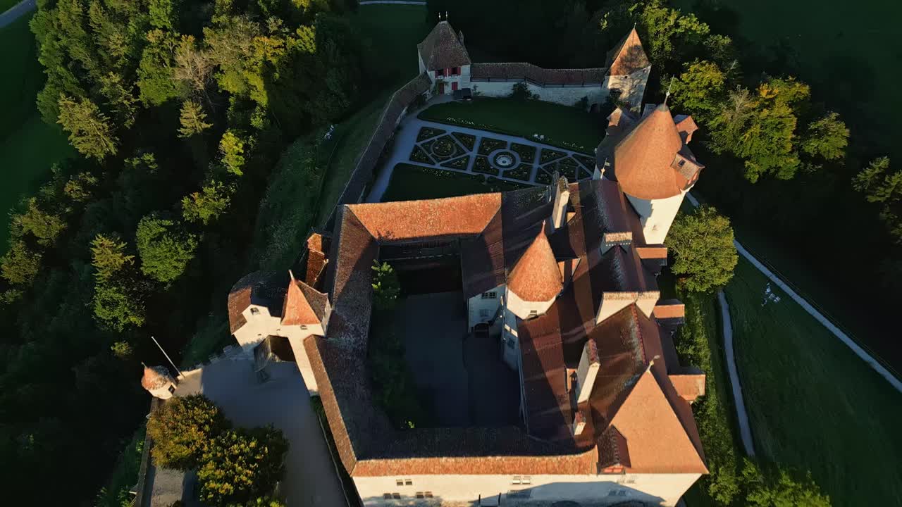 Push in tilt down drone shot right above Gruyeres Castle at sunset in Canton of Fribourg in Switzerland.