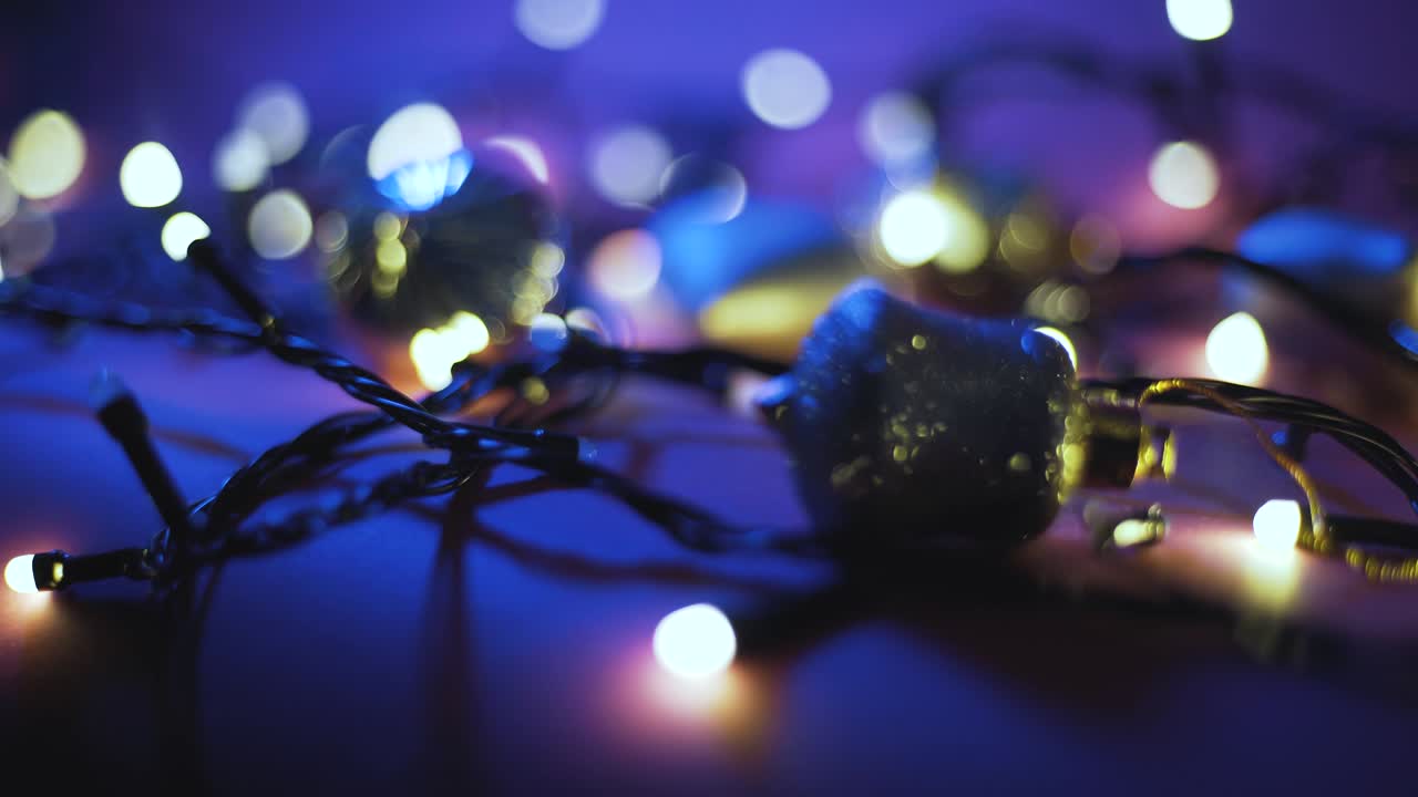 Close-up shot of garland with golden lights and christmas toys on color background. Christmas concept. Home decor. Beautiful bokeh