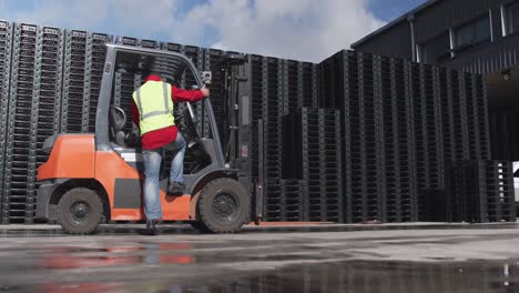 Warehouse-worker-driving-forklift-outside-factory