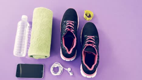 Mobile-phone-with-headphones,-shoes,-water-bottle,-napkin-and-measuring-tape