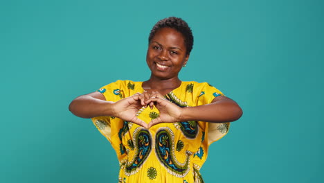 natural feminine woman showing a sweet heart shape symbol in studio