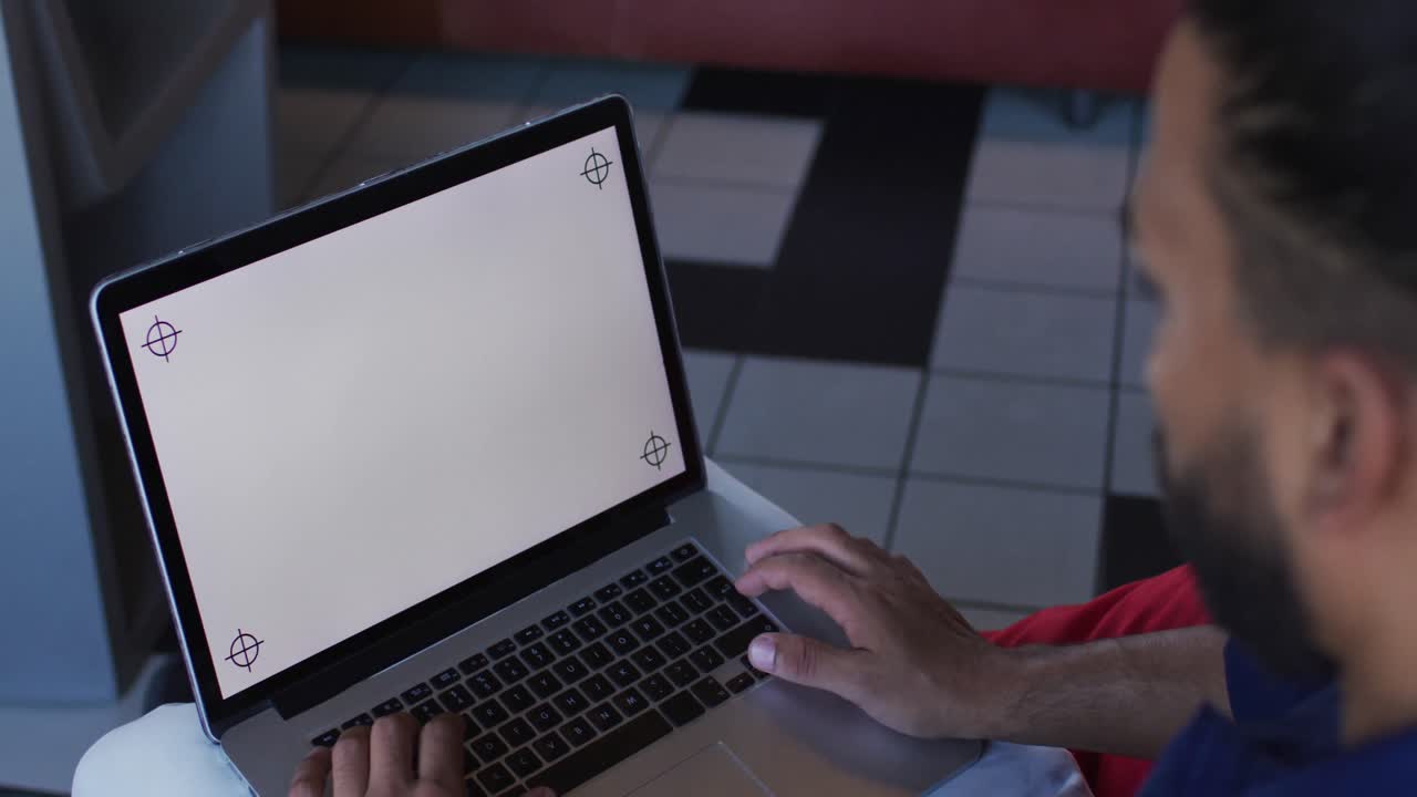 hombre de raza mixta feliz sentado en una cafetería usando una computadora portátil