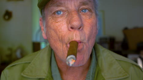 Man-in-his-mid-60s,-baby-boomer,-chain-smoker,-puffing-a-cigar-and-blowing-smoke-at-the-camera