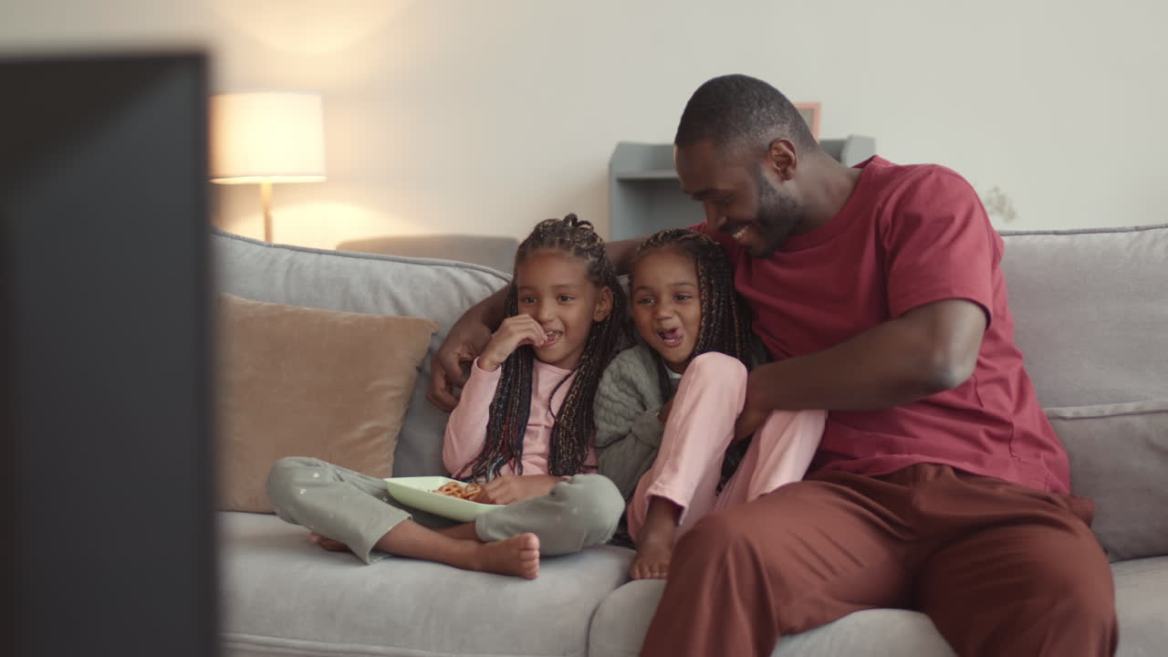 Papà che guarda la TV con le figliolette