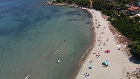 Larga-Playa-De-Arena-Blanca-Con-Turistas-Bajo-Coloridas-Sombrillas-Experimentando-Vacaciones-De-Verano-En-Cerdeña,-Italia