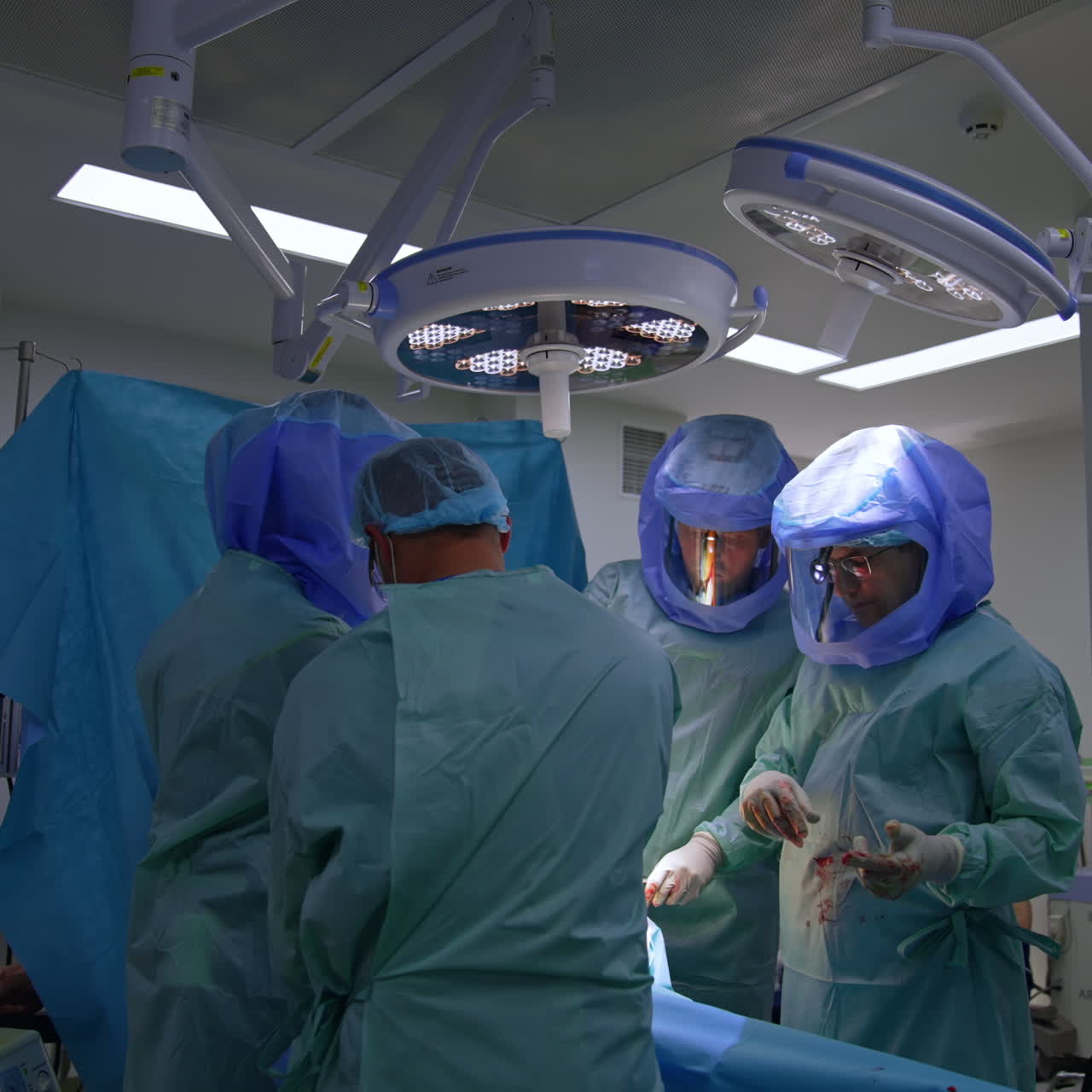 Team chirurgico collabora a un'operazione ortopedica. Medici con caschi protettivi eseguono un intervento di chirurgia traumatologica