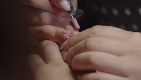 manicurist polishing a client's fingernails at the women's beauty salon, close up