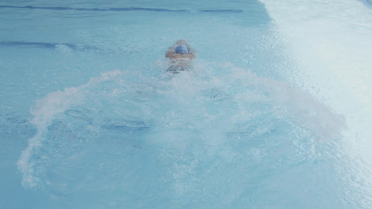 수영 선수가  모자를 입고 수영장에 뛰어들고 개구리 스타일로 수영을 하는 모습