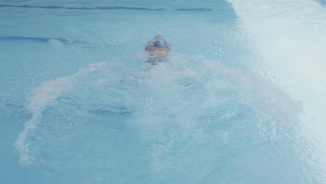 back view of swimmer wear white cap jump into pool and doing frog style swimming