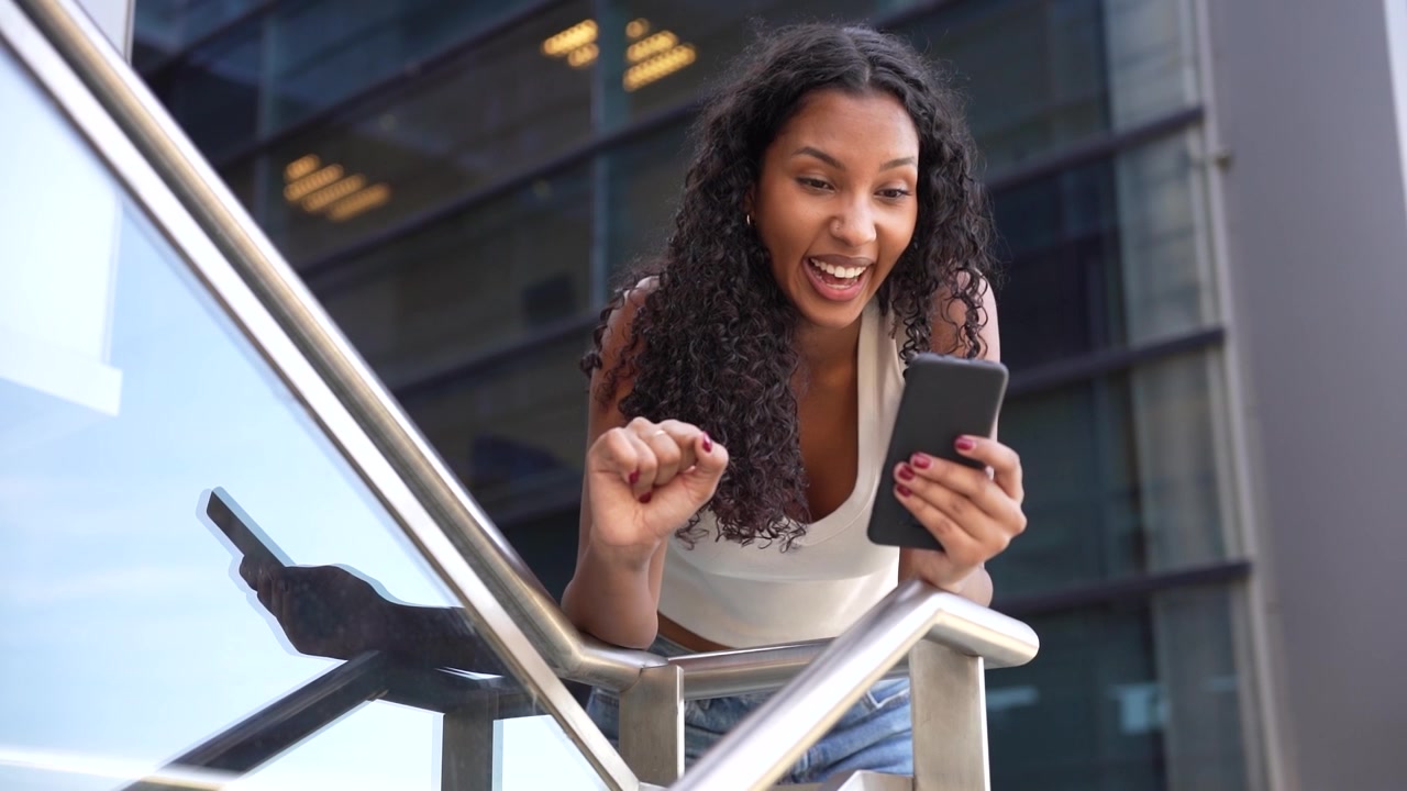 Una giovane donna attivamente impegnata con il suo smartphone sullo sfondo di un moderno paesaggio urbano.