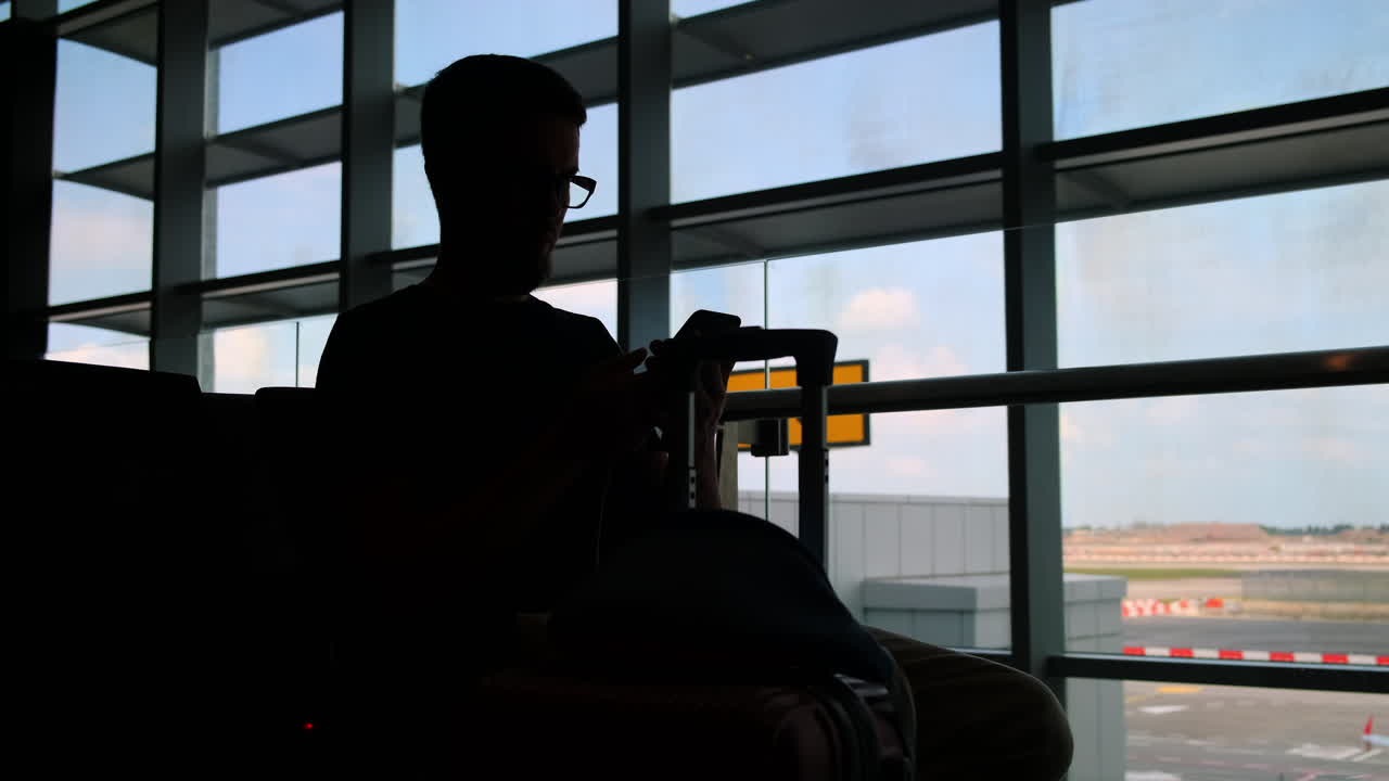 silueta de una persona usando un teléfono inteligente en el aeropuerto