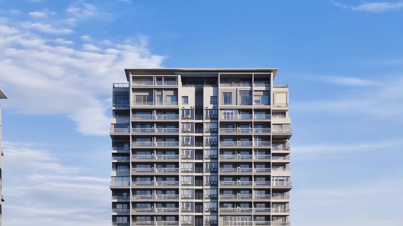 Vista frontal de um edifício residencial moderno de média altura, centralizado no quadro, com múltiplas varandas empilhadas, janelas de vidro e grades de metal. Luz natural suave de