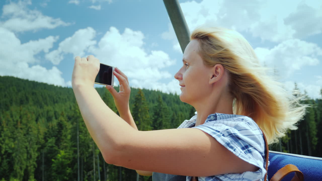 una mujer de mediana edad toma fotografías de hermosos paisajes se sienta en un banco de un remonte de vacaciones en